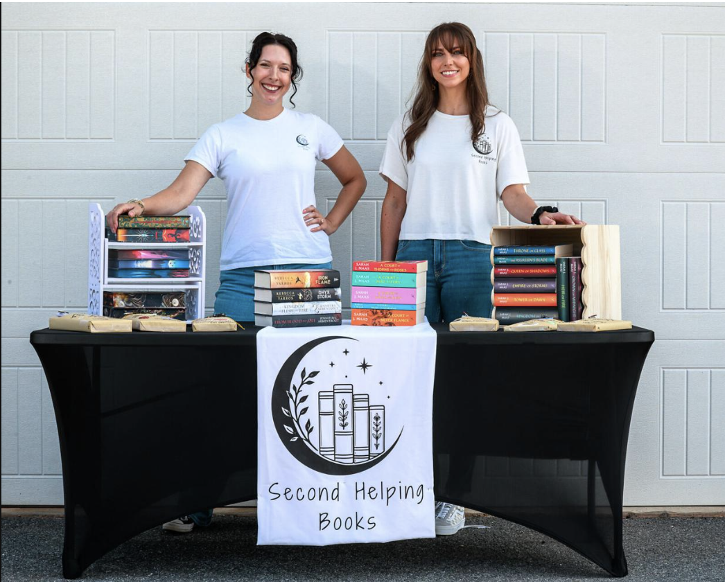 The Second Helping Books founders standing behind their book display